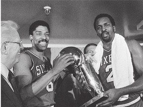Philadelphia 76ers Julius Erving, left, and Moses Malone, hold the NBA Championship trophy after defeating the Los Angeles Lakers on May 31, 1983. Malone, a three-time league MVP, died Sunday at the age of 60.