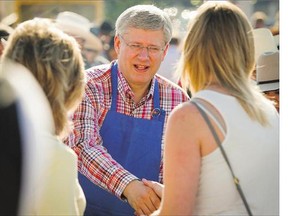 Prime Minister Stephen Harper shakes hands as he serves pancakes at a Stampede breakfast in Calgary in 2014. Harper, Tom Mulcair and Justin Trudeau are all expected Friday at this year's Stampede jockeying for voter approval.