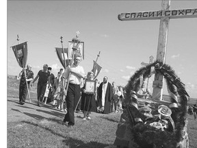 A religious procession passes an Orthodox cross with a sign reading Save and Guard at the crash site of Malaysia Airlines Flight 17, which was shot down one year ago, near the village of Hrabove, Ukraine, on Friday.