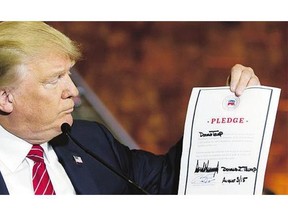 Republican presidential candidate Donald Trump looks at a signed pledge that rules out a possible third-party White House bid during a news conference Thursday.