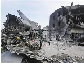 Rescuers search for victims at the site where an Indonesian air force transport plane crashed in Medan, North Sumatra, Indonesia Wednesday. The C-130 Hercules plane crashed into a residential neighbourhood killing 141 people.