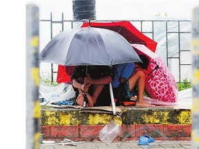 Residents huddle under their umbrellas as strong winds and slight rain are brought by Typhoon Koppu in Manila.