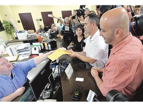 Rowan County deputy clerk Brian Mason, left, hands a marriage licence to a gay couple at the Rowan County Judicial Center in Morehead, Ky., earlier this month.