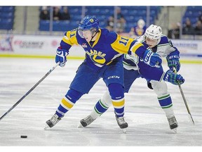 Saskatoon Blades' Luke Gingras stickhandles with one arm keeping away Artyom Minulin of the Swift Current Broncos during first period in Saskatoon, Friday.