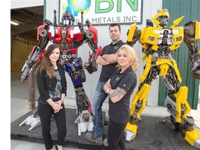 Stacey Heistad, left, office manager Sherri McEwen and President Mark Riffel with the 2 transformers in the parking lot at BN Steel&Metal. The 2 transformers are build out of materials from the large steel piles out back of the shop, August 26, 2015. (GordWaldner/TheStarPhoenix)