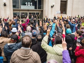 Participants in the Refugees Welcome rally in Saskatoon raised their hands in peace signs in response to a man trying to shout down one of the speakers.