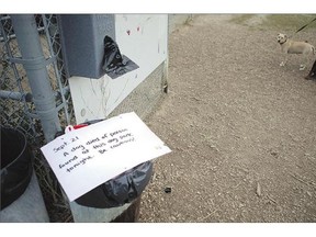 A sign that was pulled out from a garbage can warns dog owners of an alleged dog poisoning at Avalon off-leash dog park on Tuesday.
