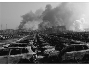 Smoke billows Thursday behind rows of burned-out Volkswagen cars at the site of a series of explosions in Tianjin, a petrochemical processing hub about 120 kilometres east of Beijing. There was no indication of what caused the disaster in one of China's busiest ports.