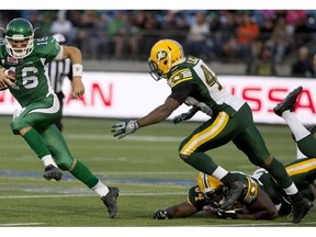 Saskatchewan Roughriders' Brett Smith (16) dodges the tackle from Edmonton Eskimos' Ryan Hinds (34) and Deon Lacey (40) during second half CFL pre-season action in Fort McMurray, Alta., on Saturday June 13, 2015. THE CANADIAN PRESS/Jason Franson.