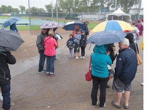 Steady rain in the city had people using innovative means to stay dry, including backpacks and shopping bags along with standard umbrellas, August 6, 2015. Here fans at Cairns Field arrive to find the Team Saskatchewan baseball game postponed.