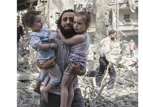 A Syrian man carries his daughters through rubble following a bomb attack earlier this month in the city of Aleppo.