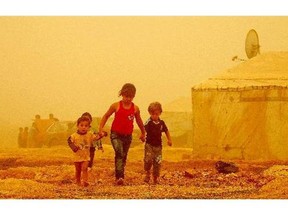 Syrian children walk amid the dust during a sandstorm at a refugee camp on the outskirts of the eastern Lebanese city of Baalbek on Monday.