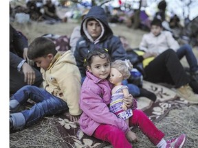 Syrian refugees and migrants gather Tuesday near Turkey's border with Greece. A group of former bureaucrats is urging Prime Minister Stephen Harper to provide the political direction required to fast-track applications from Syrian refugees trying to get to Canada.