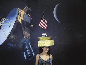 Tara Kedia wears a New Horizons probe hat Tuesday at the Johns Hopkins University Applied Physics Laboratory in Laurel, Md. The unmanned NASA spacecraft passed by Pluto on Tuesday, making its closest approach in the climax of a decade-long journey to explore the dwarf planet for the first time, NASA said.