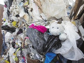 A teddy bear peeks out of a heap of garbage , one of many items improperly disposed of in apartment recycling bins . The practice is putting nancial strain on the city program.