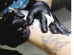 Terry 'Tree' Fenrick, tattoo artist at INKognito Tattoos, inks a semicolon tattoo on Regina Leader-Post reporter Emma Graney in Regina on Friday.
