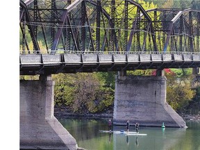 Three paddle boarders go under the Victoria Bridge during a sunny outing on the river Thursday.