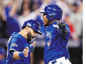 Toronto Blue Jays' Jose Bautista, left, and Edwin Encarnacion celebrate after scoring on a three-run double by Troy Tulowitzki during the sixth inning of Game 5 of the American League Championship Series against the Kansas City Royals in Toronto on Wednesday. See full coverage on C1, C3.