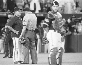 Toronto Blue Jays manager John Gibbons, left, confers with home plate umpire Dale Scott on the controversial play involving Jays catcher Russell Martin Wednesday night in Toronto. It took 18 minutes for the umpires to make the call.
