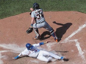 Toronto Blue Jays' Ryan Goins slides into home plate as he scores on an RBI single by Josh Donaldson in front of Detroit Tigers catcher James McCann in Toronto on Sunday. The Jays won the game 9-2 to sweep the series.