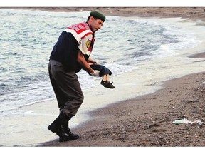 A Turkish paramilitary police officer carries the lifeless body of a migrant child after boats carrying migrants to the Greek island of Kos capsized on Wednesday.