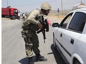 A Turkish soldier checks cars at a checkpoint in Diyarbakir on Sunday following the death of two Turkish soldiers in a car-bomb attack in the Kurdish-dominated southeast of the country following air strikes on PKK Kurdish rebels.