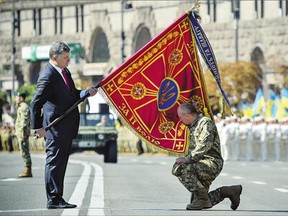 Ukraine's President Petro Poroshenko hands over a flag of a military unit as a soldier kisses the flag before a military parade on the occasion of Ukraine's Independence Day in the capital of Kyiv on Monday.