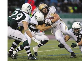 University of Saskatchewan Huskies defenders, from left, Spencer Krieger, Dylam Kemp and Dane Bishop wrap up running back Alex Christie of the University of Manitoba Bisons at Griffiths Stadium on Friday.