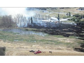 A water bomber flies above a field where fire crews work in the LaRonge, Sask., area in this July 1, 2015 handout photo from the Saskatchewan Ministry of Environment. THE CANADIAN PRESS/HO - Saskatchewan Ministry of Environment - Wildfire Branch