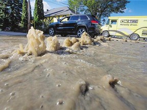 Water gushes through the broken pavement during a water main break in the 1400 block of Kilburn Avenue on Monday.