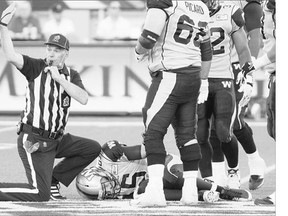 Winnipeg Blue Bombers' Drew Willy, centre, grimaces in pain during Sunday's CFL game in Hamilton. Willy suffered a leg injury that will put him out of the lineup for up to 6-8 weeks.