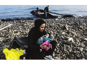 A woman holds her child after arriving with other migrants on the Greek island of Lesbos after crossing the Aegean Sea from Turkey. The Greek coast guard said five more migrants, including a baby and two boys, died on the crossing.