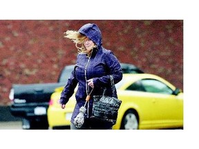 A woman makes her way across Victoria Avenue in downtown Regina on Tuesday. Environment Canada is warning residents in southern Saskatchewan to prepare for extreme winds today as downpours subside.