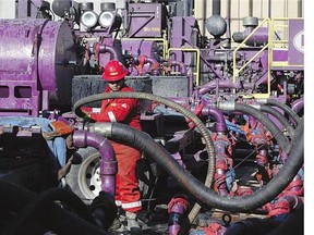 A worker adjusts hoses during a hydraulic fracturing operation at an EnCana gas well, near Mead, Colo.