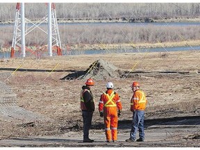 Workers stand near the scene where a 55-year-old pilot and a passenger, 30, died in a helicopter crash some 13 kilometres north of the Paynton Ferry on Thursday.