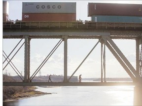 Workers travel across the bottom of the train bridge near the Circle Drive South Bridge on Sunday.