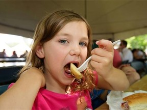 Six-year-old Kiera Landry of Regina chows down on a perogie from Riviera Restaurant as part of a busy lunch crowd in the tents and in the sunshine as the annual Taste of Saskatchewan kicked off in Kiwanis Park, Tuesday, July 15, 2014.