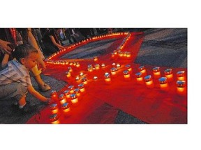 A young Serbian boy lights a candle in remembrance of those lost to AIDS in Belgrade in 2006. A new study has found continued inequalities in life expectancy among Canadians diagnosed with HIV.