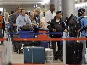 FILE - In this May 22, 2015 file photo, travelers wait in line to check in their luggage at Miami International Airport in Miami. Heading into winter, fliers should take extra precautions with their checked luggage, December and January are traditionally the worst months for lost bags. (AP Photo/Alan Diaz)