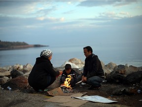 A refugee family from Afghanistan warm themselves around a fire in Greece. Dozens of rafts and boats continue to make the journey from Turkey to Lesbos each day as thousands flee conflict in Iraq, Syria, Afghanistan and other countries.