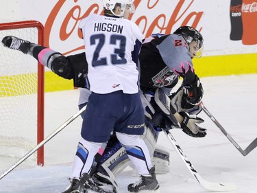 Calgary Hitmen's Aaron Hyman is pulled down in front of Saskatoon Blades goalie Brock Hamm by Blades' Schael Higson in WHL action at the Scotiabank Saddledome in Calgary, November 22, 2015.