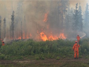 Firefighters battle a wildfire near La Ronge, Saskatchewan, Sunday, July 5, 2015. Fires and smoke have forced about 9,000 people from their homes in more than 50 communities in the northern part of the province.