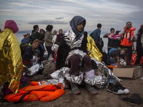 Refugees are helped by volunteers after crossing the Aegean sea on a dinghy from the Turkey's coast to the northeastern Greek island of Lesbos, on Tuesday, Nov. 24, 2015.