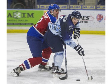 Saskatoon Blades forward Cameron Hausinger moves the puck away from Edmonton Oil Kings defenceman Kyle Yewchuk in second period WHL action, November 28, 2015.
