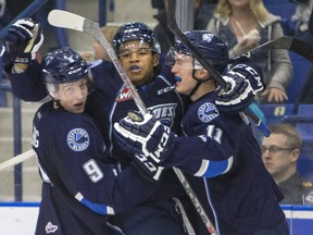 Saskatoon Blades defenceman Tyler Dea, centre, celebrates his first WHL goal with teammates  Cameron Hebig, left, and Luke Gingras against the Vancouver Giants during the second period of WHL action on Sunday, Oct. 4, 2015.