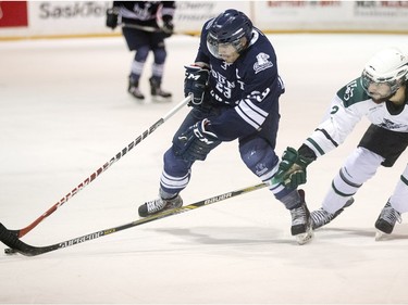 University of Saskatchewan Huskies' Kendall McFaull (R) and Mount Royal Univeristy Cougars' Tyler Fiddler battle for the puck  on November 27, 2015 in Saskatoon.