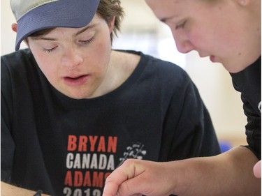A volunteer helps Ben Shear with a province of Saskatchewan shaped decoration at decorating bee where Special Olympic Athletes spent the afternoon cutting, drawing and glueing hand made tree decorations before placing them on the tree bound for the 2015 City Hospital Foundation's Festival of Trees at the WDM, Nov. 12, 2015. All decoration represented the sports the participant are involved in. Volunteer parents and high school students from Holy Cross and Bishop James Mahoney High Schools also spent the afternoon helping out.