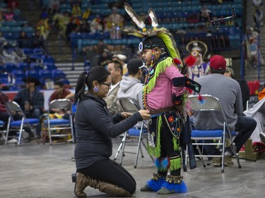 A dancer has some last-minute adjustments made prior to taking part in the opening ceremonies  during the Federation of Saskatchewan Indian Nations (FSIN) Cultural Celebration and Pow Wow at SaskTel Centre in Saskatoon, November 15, 2015.