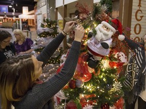 The annual Festival of Trees is here and volunteers Jai-Lyn Melnychuk, right and Jasmin Orgren add the finishing touches on the Special Olympics tree that Saskatoon Special Olympian participants decorated with hand made ornaments, November 19, 2015. The tree was one of the first setup and ready with the 2015 opening the next day all at Western Development Museum.