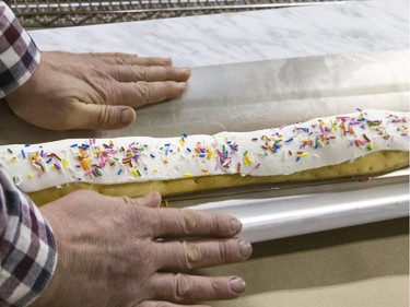 SASKATOON, SASK.; NOVEMBER  24, 2015 - 1125 news donut   Keith Jorgensen hands help with the cooked 19 foot long john cooked in this eavestrough then moved to tables keeping it in the eavestrough but flattening the eavestrough sides open. NestorÕs Bakery where students of the Community LearnerÕs High School are attempting to make the worldÕs longest long john donut measuring in at over 19' 1 1/2 "  November 24, 2015. Keith Jorgensen with helpers Randy Shaw, Anna Weird, Janet Neu, Tom Carey and Carmen Dyck all participated.  (GORD WALDNER/Saskatoon StarPhoenix)